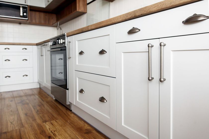 Cuisine moderne avec armoires, four en acier inoxydable et parquet.