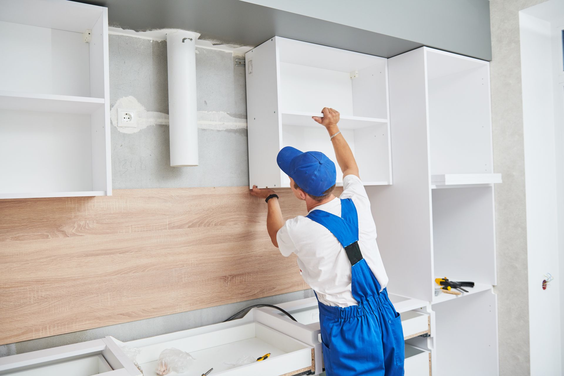 Ouvrier installant des armoires de cuisine dans une cuisine moderne.