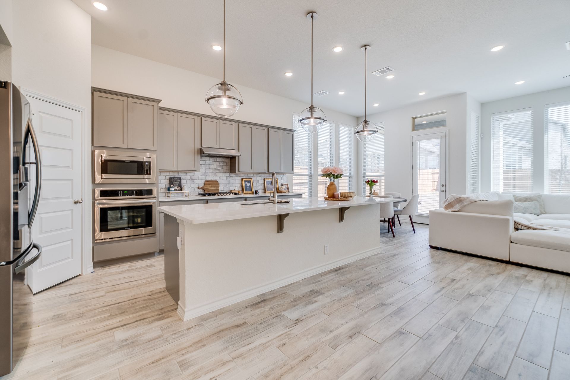 Cuisine et salon modernes et lumineux avec armoires, îlot et parquet.