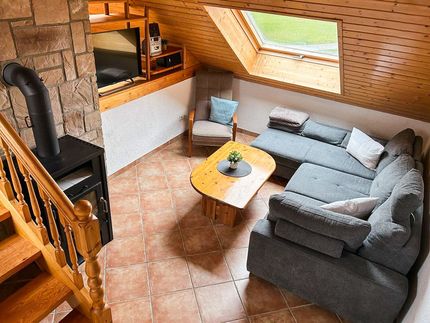 Kaminzimmer mit Sitzecke und Kamin unter einer Dachschraege mit Fenster im Hof Gottesbueren bei Warburg, direkt am Diemelradweg gelegen