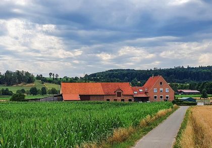 Aussenansicht der Pension Hof Gottesbueren am Diemelradweg nahe Warburg, umgeben von Felder, Wald und Wiesen