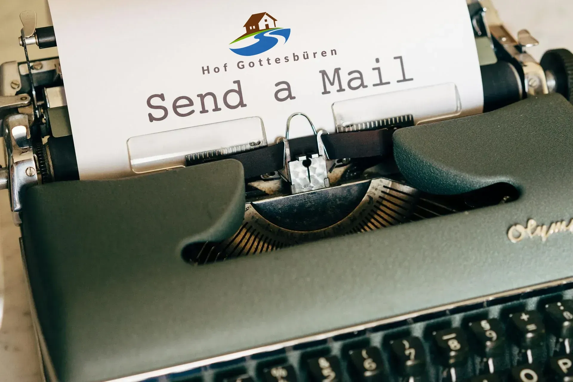 Schreibmaschine mit Blatt Papier. Logo vom Hof Gottesbüren und send a mail steht auf dem Papier.