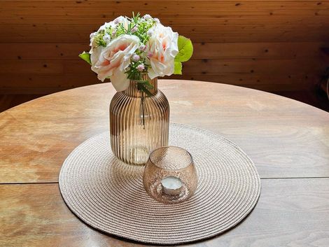Blumenvase mit Blumen auf einem Tisch mit Untersetzer im Hof Gottesbueren am Diemelradweg nahe Warburg