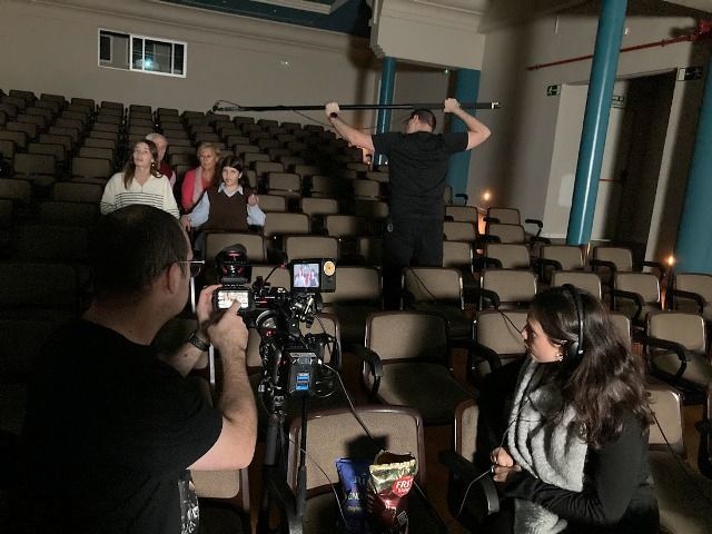 Un hombre está tomando una fotografía de un grupo de personas en un auditorio.