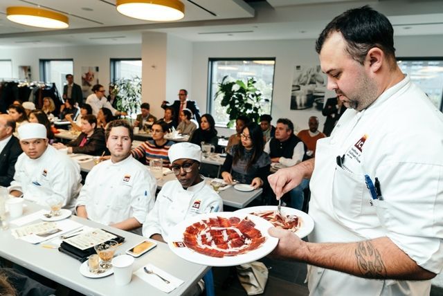 Un hombre sostiene un plato de comida frente a un grupo de personas.