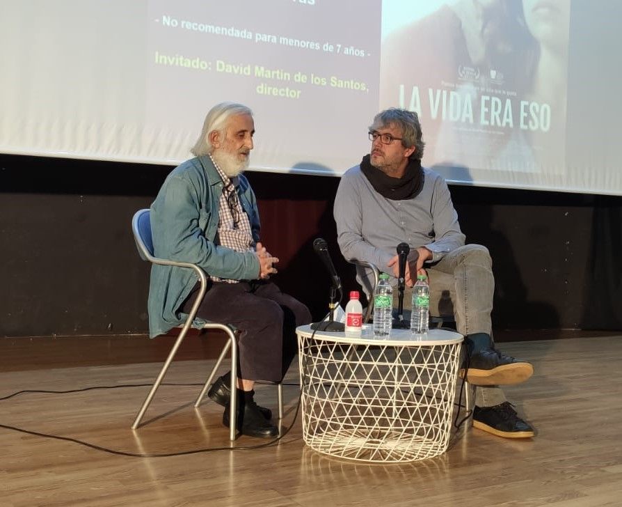 Dos hombres están sentados frente a una pantalla que dice la vida era eso