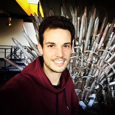 Un hombre se toma una selfie frente a un trono hecho de espadas.