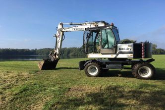 Weißer Bagger auf einer Wiese