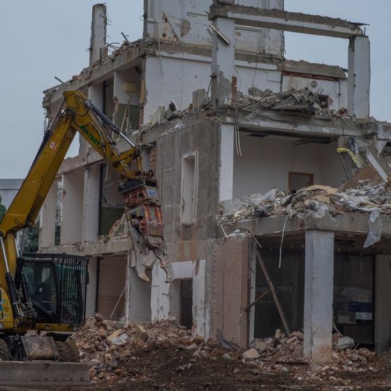 Bagger nimmt ein schon großflächig zerstörtes Haus auseinander