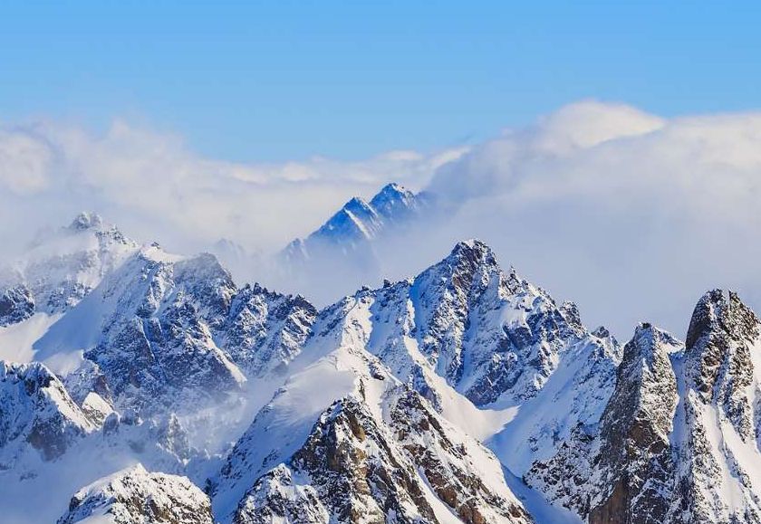 Eine schneebedeckte Bergkette mit blauem Himmel und Wolken im Hintergrund