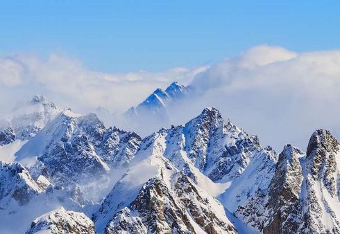 Eine schneebedeckte Bergkette mit blauem Himmel und Wolken im Hintergrund