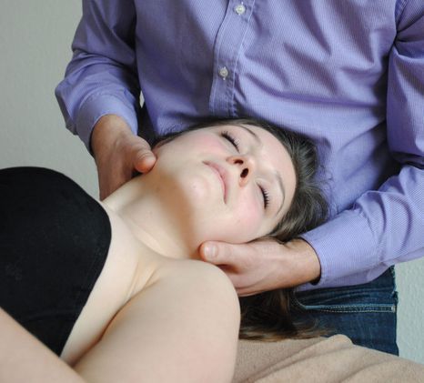 Ein Mann im lila Hemd gibt einer Frau eine Nackenmassage