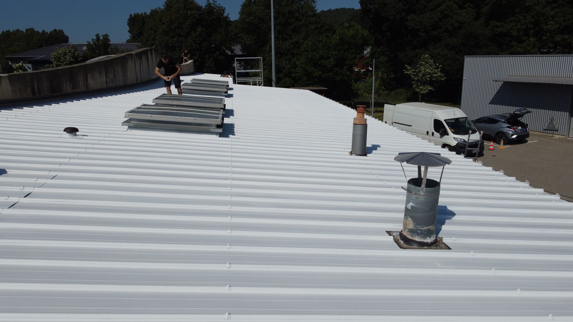 Ouvrier Stax sur un toit tout juste repeint avec de la peinture thermo-réflective