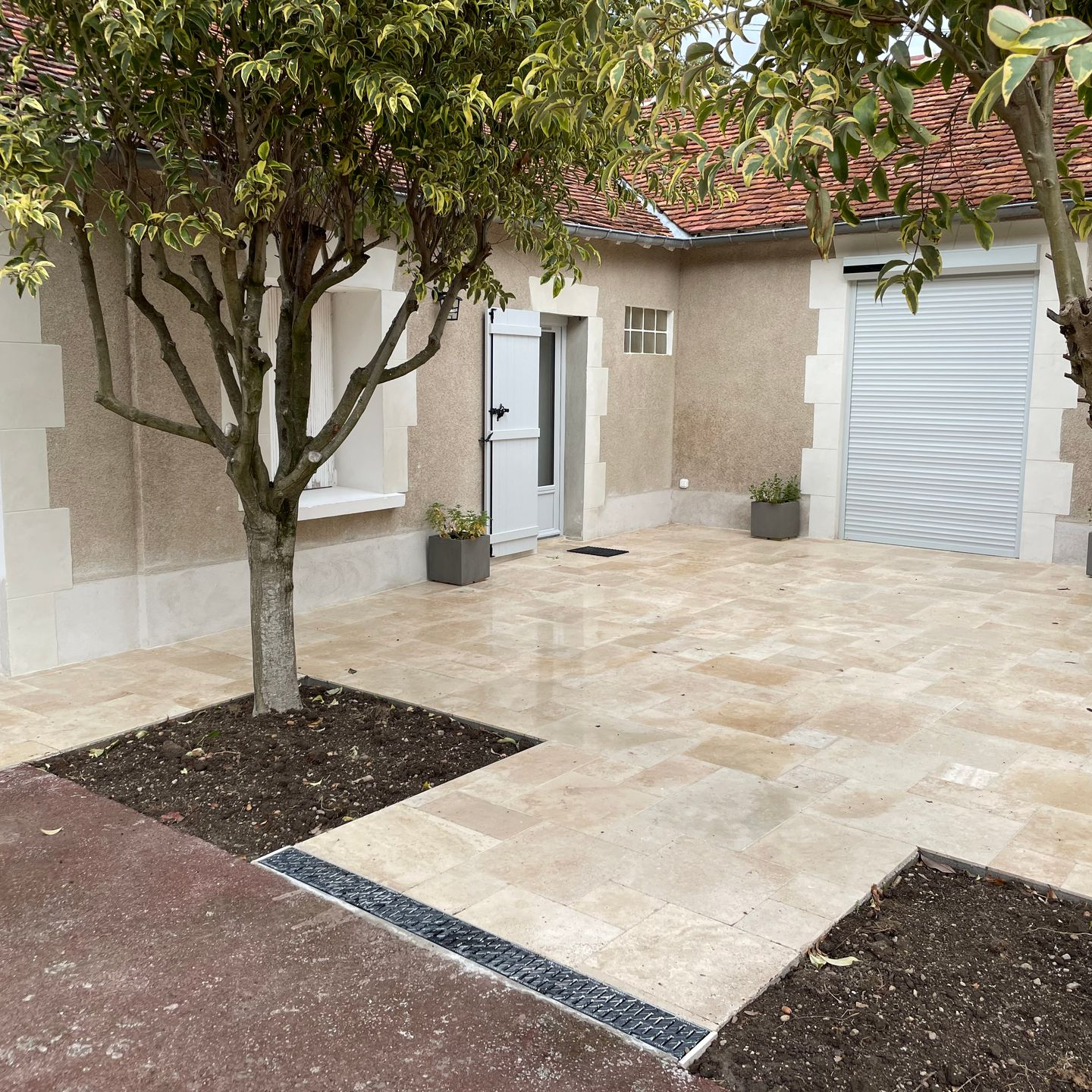 Terrasse carrelée avec 2 arbres.