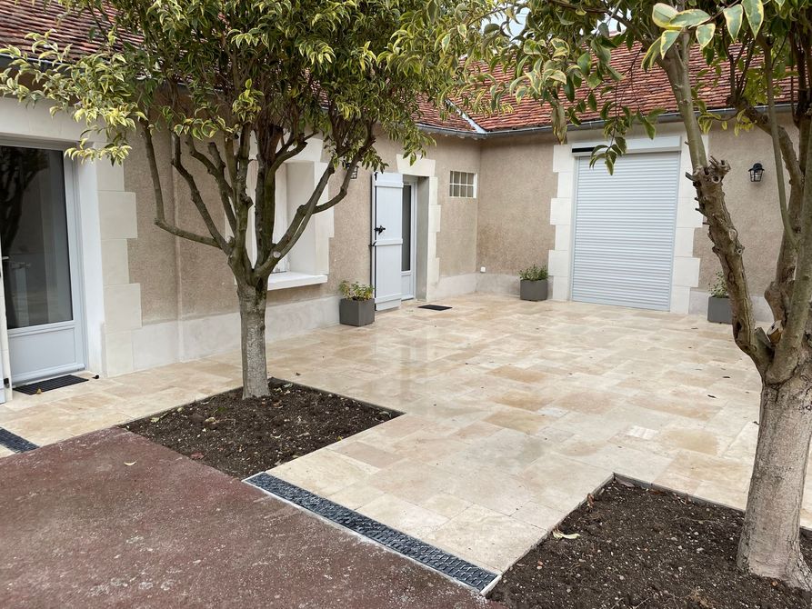 Cour intérieure avec terrasse carrelée et quelques arbres.