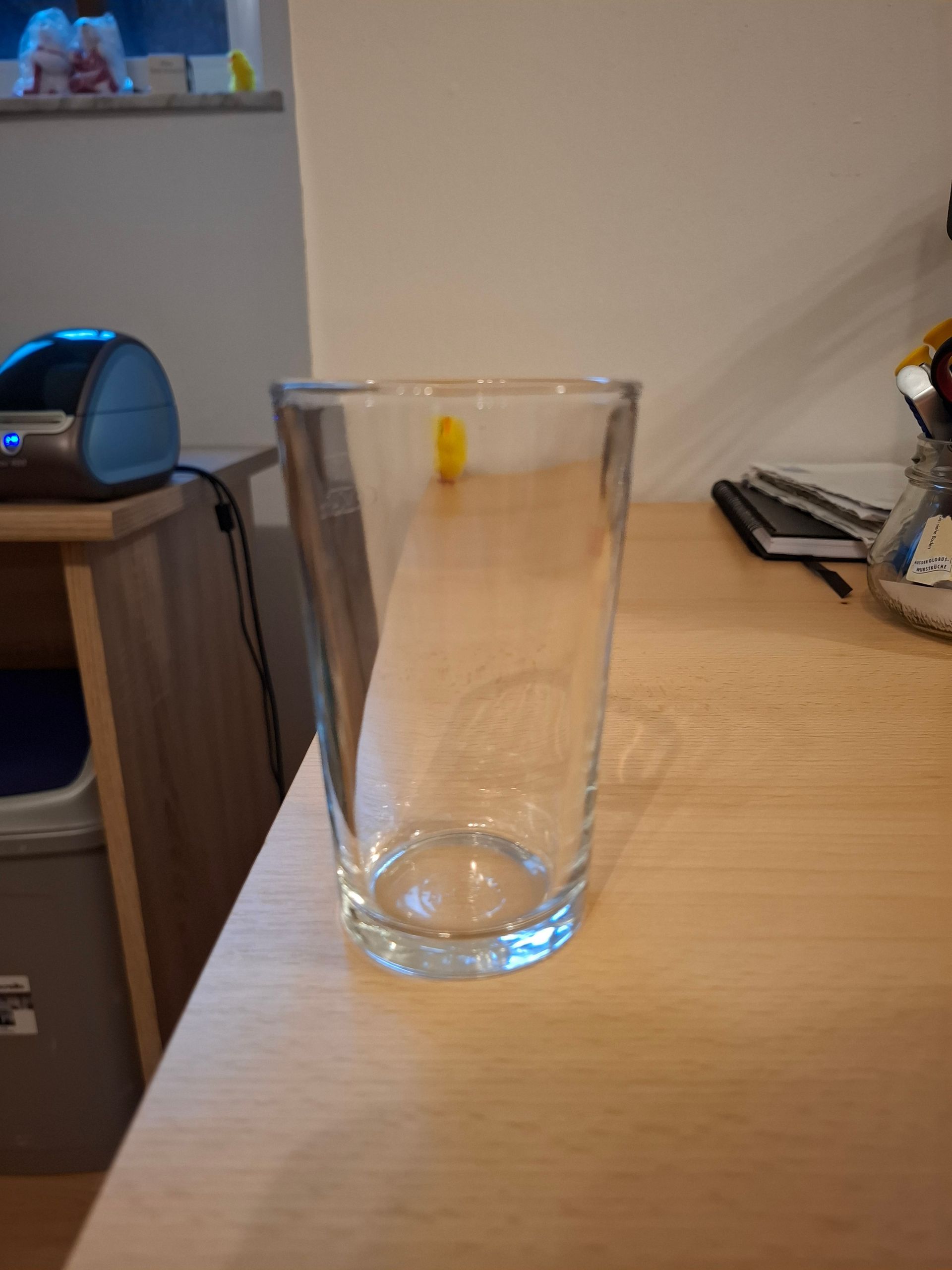 Auf einem Holztisch steht ein leeres Glas.