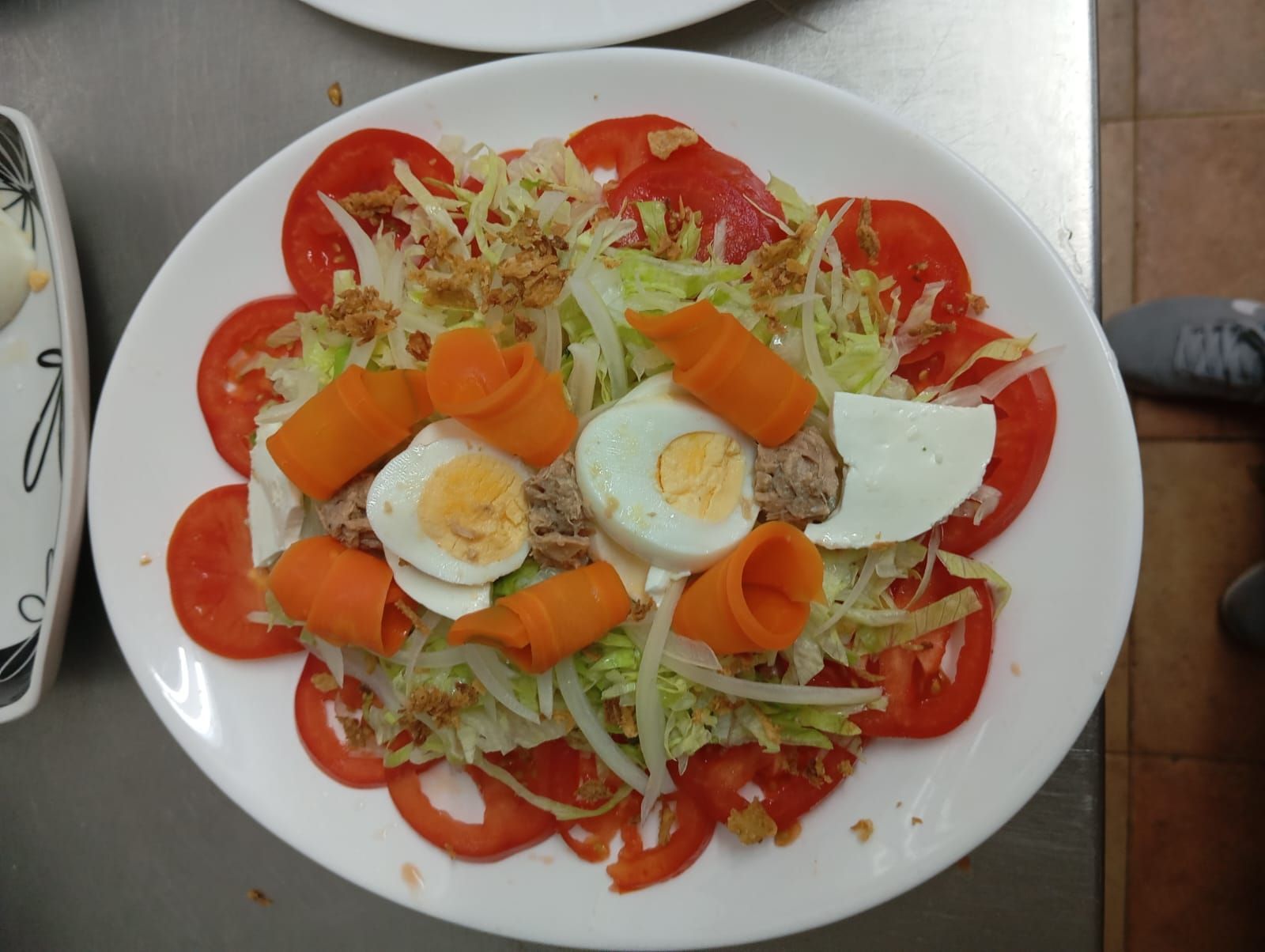 Una ensalada con tomates, zanahorias y huevos en un plato.