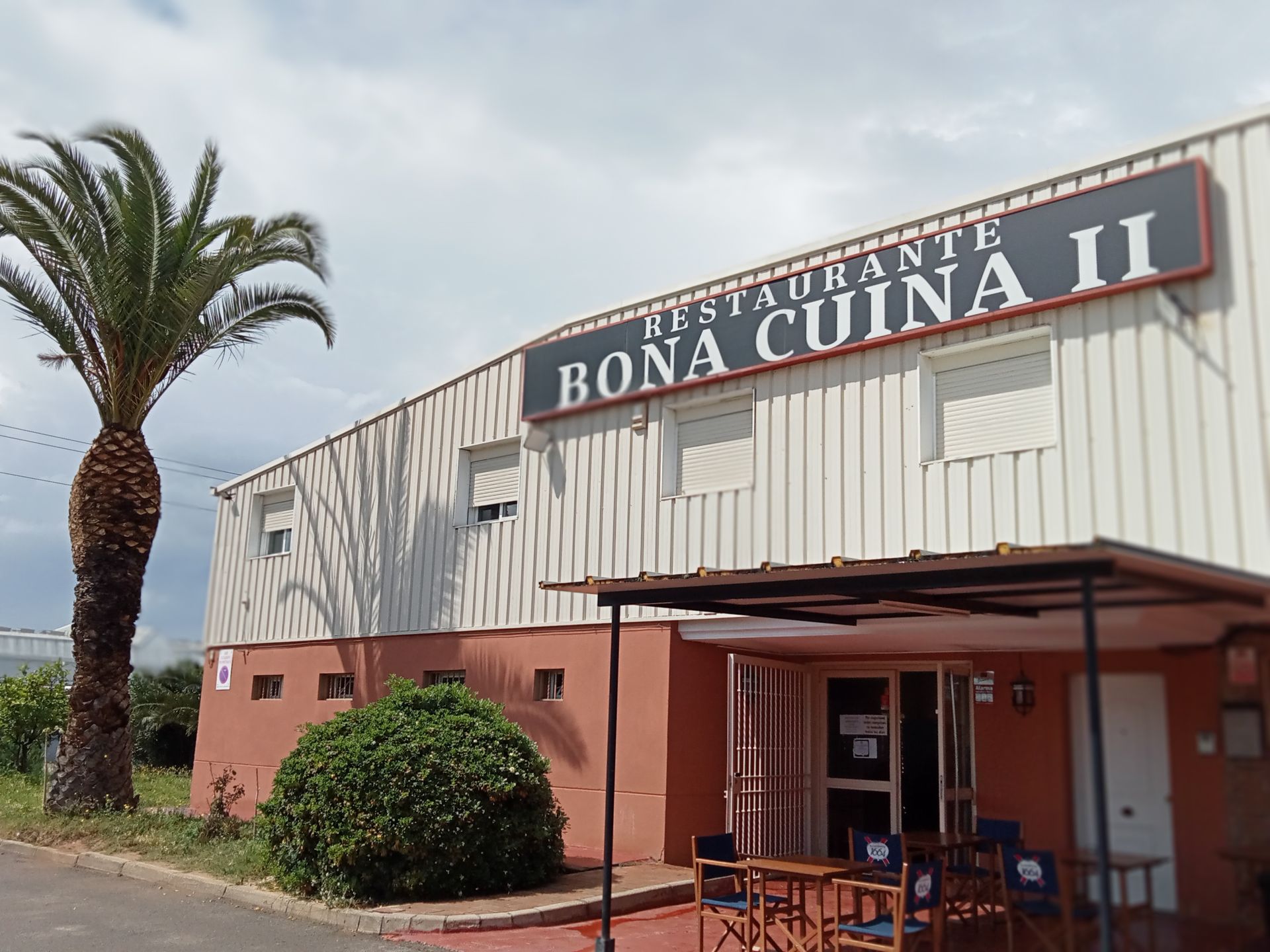 Un restaurante llamado Bona Cuina II tiene una palmera enfrente.