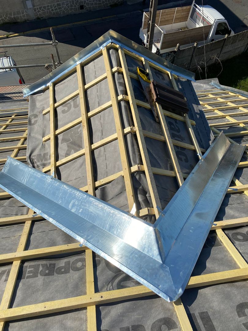 Solin de toiture métallique bleu sur un toit de tuiles autour d'une lucarne