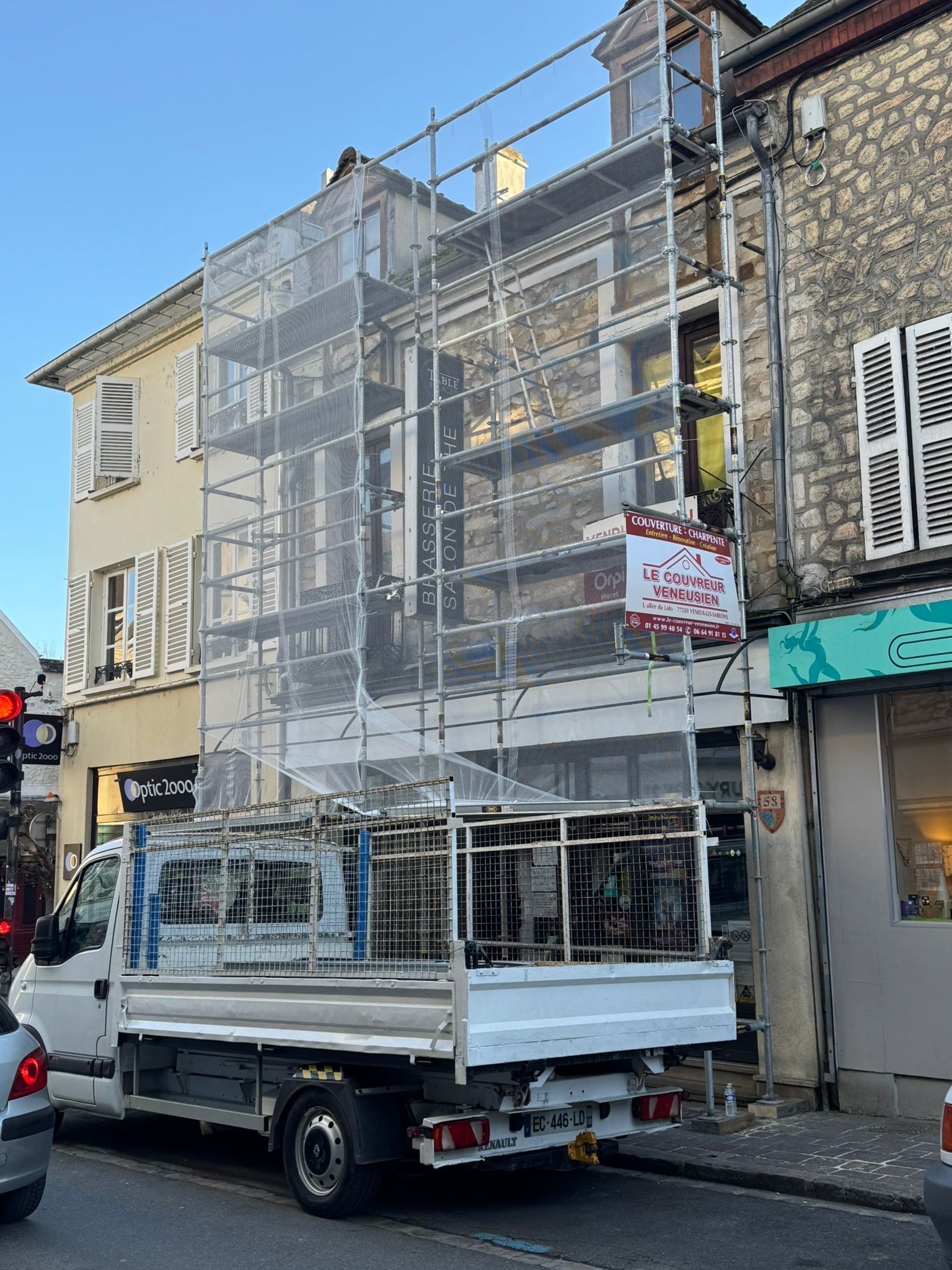 Camion transportant des échafaudages métalliques stationné dans une rue étroite à côté de vieux bâtiments