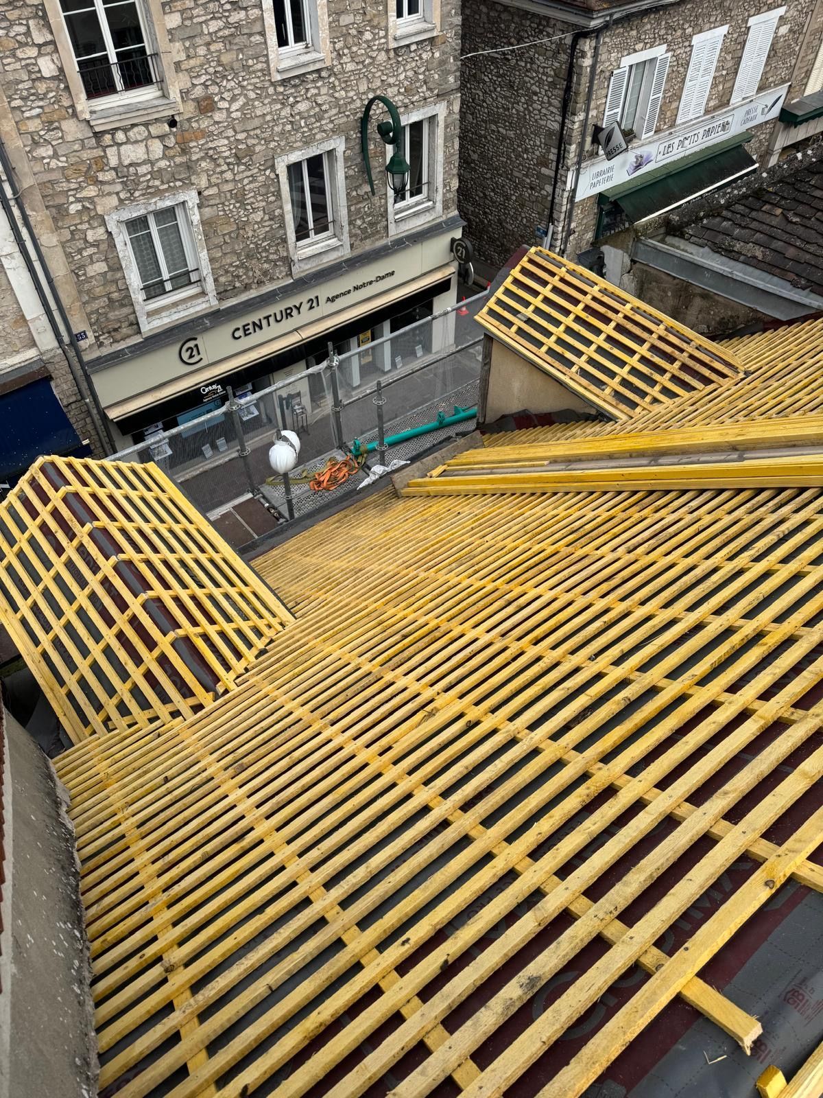 Échafaudages de toit en bois jaune à côté de bâtiments en pierre dans une scène de rue urbaine