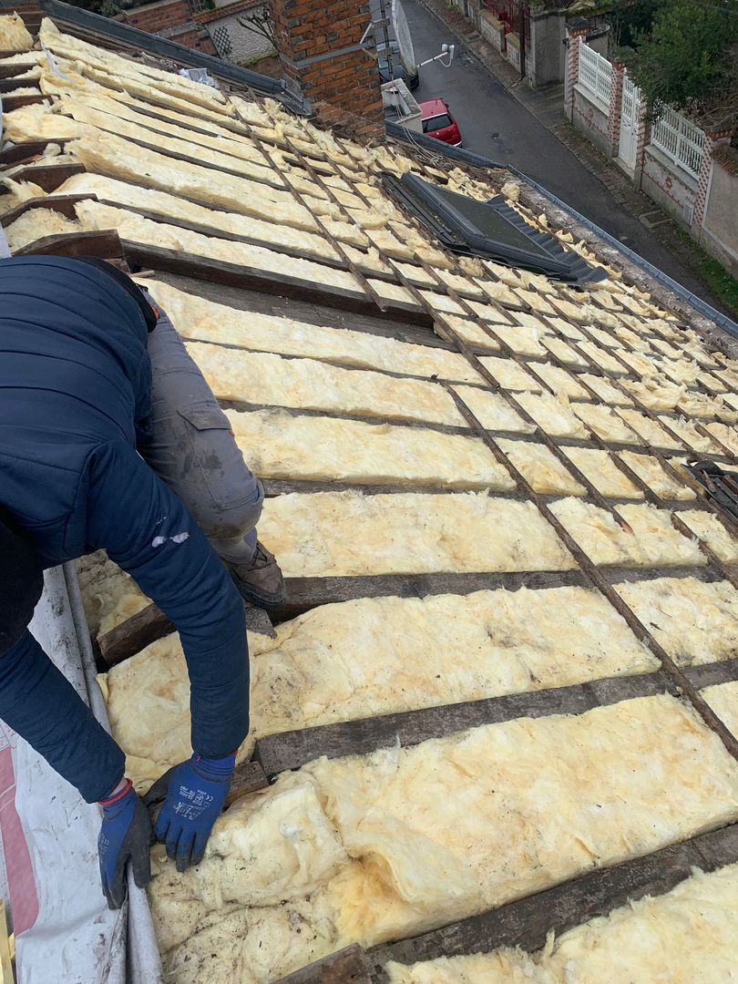 Ouvrier installant des panneaux d'isolation jaunes sur un toit pentu