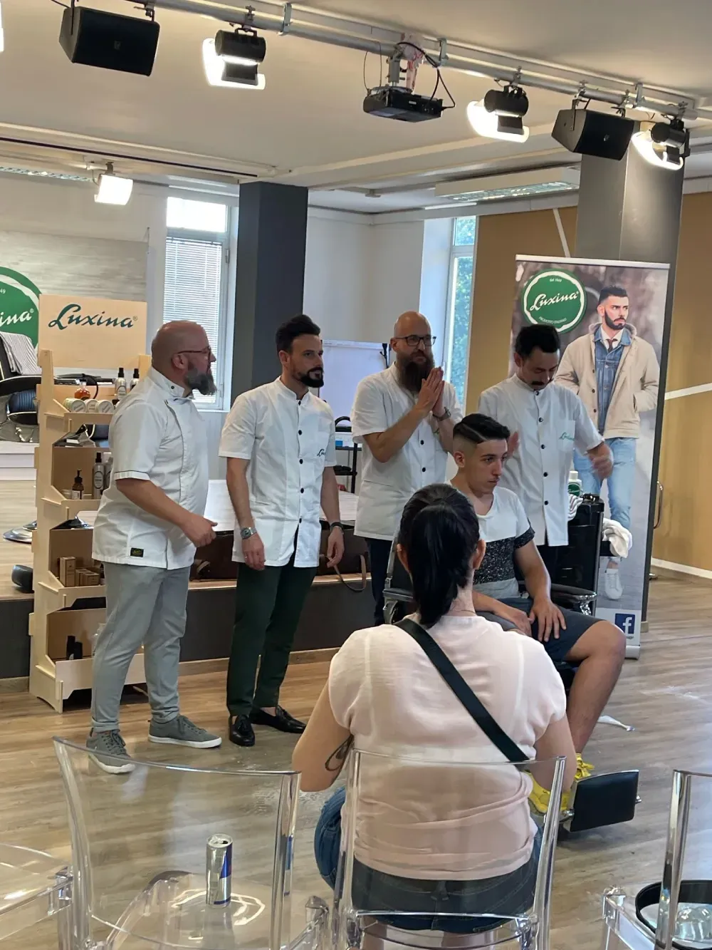 Un grupo de hombres está de pie en una habitación con una mujer sentada en una silla.