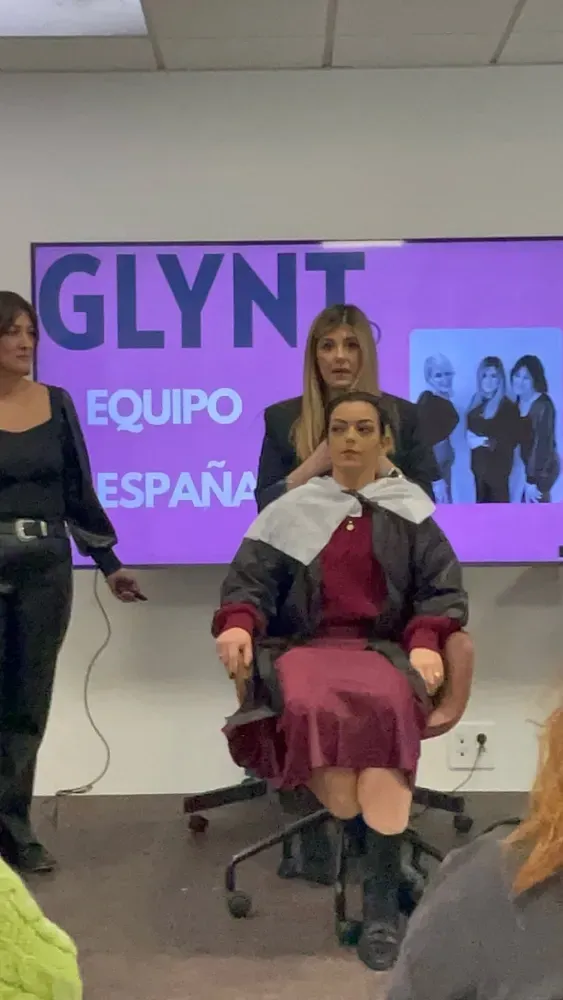 Una mujer se está cortando el pelo delante de una pantalla que dice glynt equipo espana