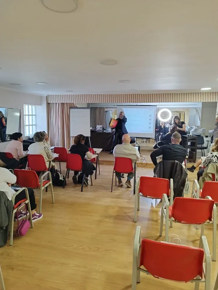 Un grupo de personas están sentadas en sillas rojas en una habitación.