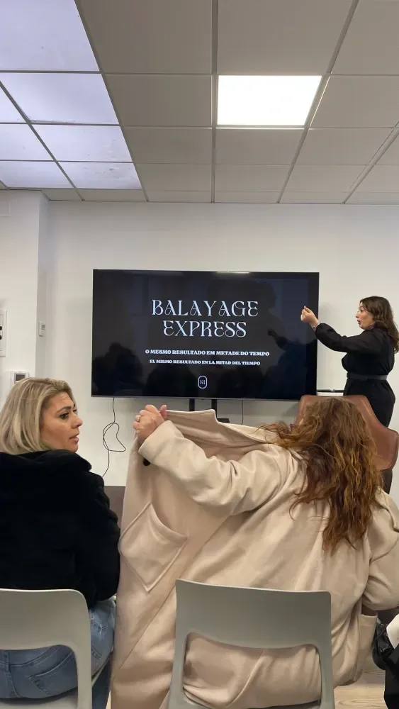 Un grupo de mujeres está sentada frente a una pantalla grande en una habitación.