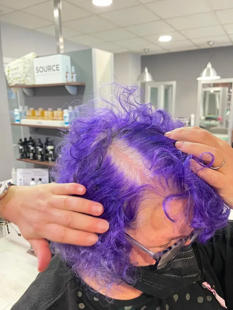 Una mujer con cabello morado se está cortando el pelo en la peluquería.