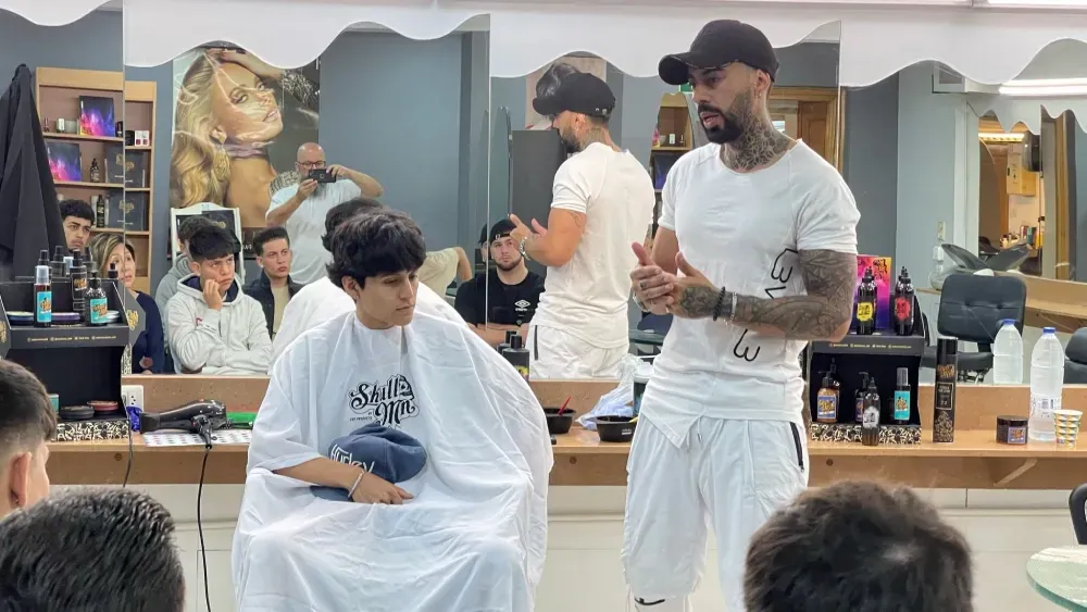 Un hombre le está cortando el pelo a un niño en una barbería.