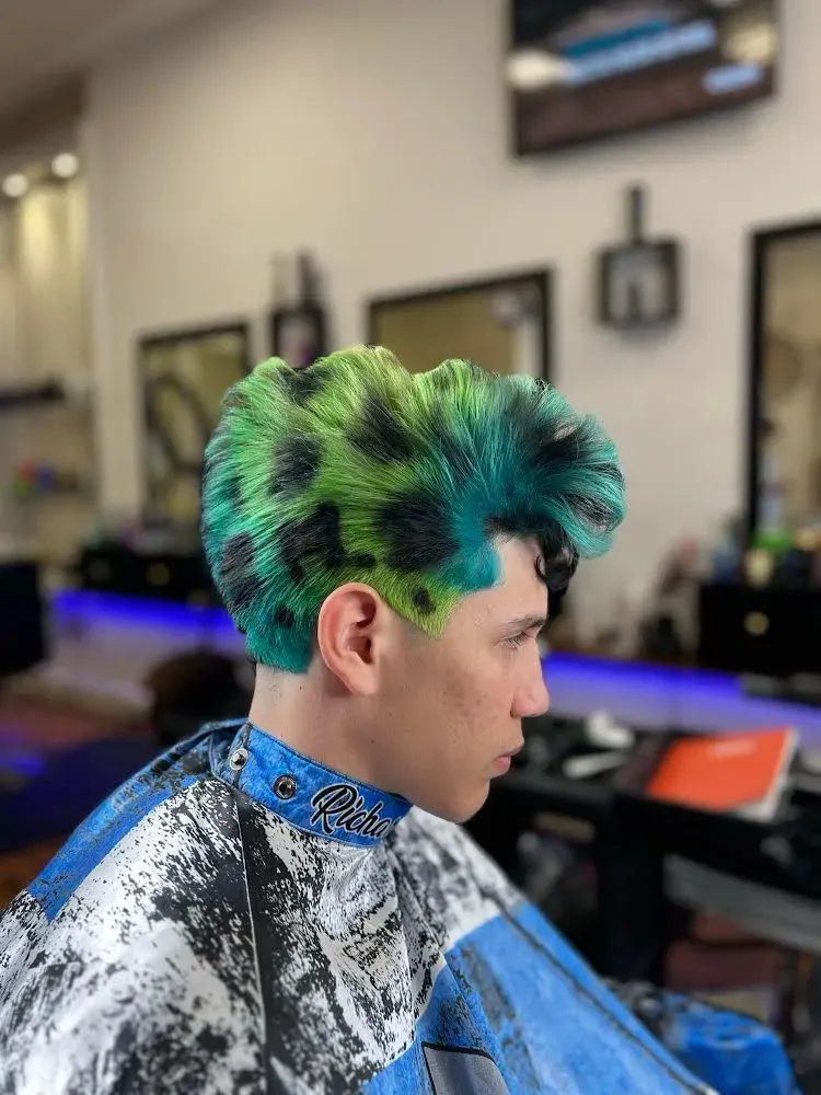 Un hombre con cabello verde y negro se está cortando el pelo en una barbería.