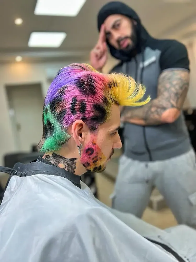 Un hombre con cabello colorido se está cortando el pelo en un barbero.