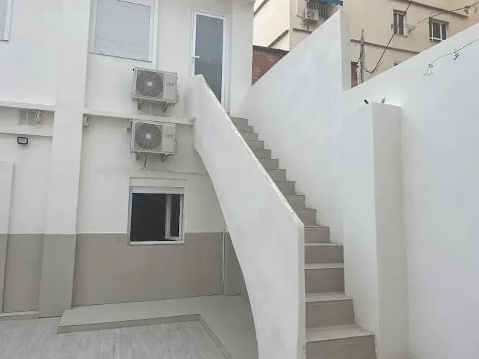 Escaleras que conducen a un edificio con dos aparatos de aire acondicionado en la pared.