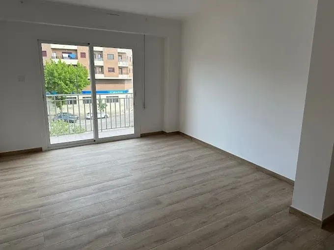 Una habitación vacía con una puerta corrediza de vidrio y un balcón.