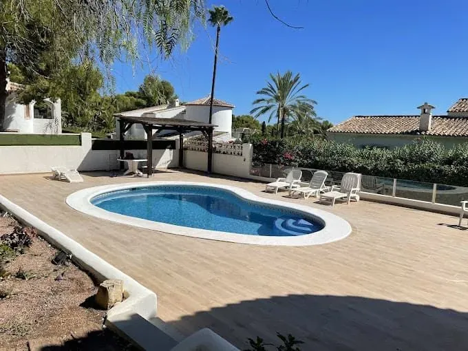 Una gran piscina rodeada de sillas y palmeras.