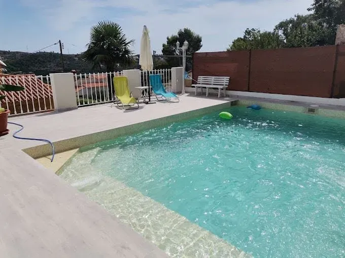 Una gran piscina con sillas y sombrillas alrededor.