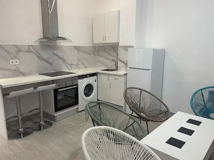 Una cocina con lavadora y secadora, una mesa y sillas.