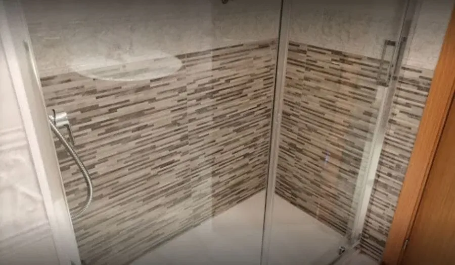 Un baño con ducha a ras de suelo y pared de azulejos.