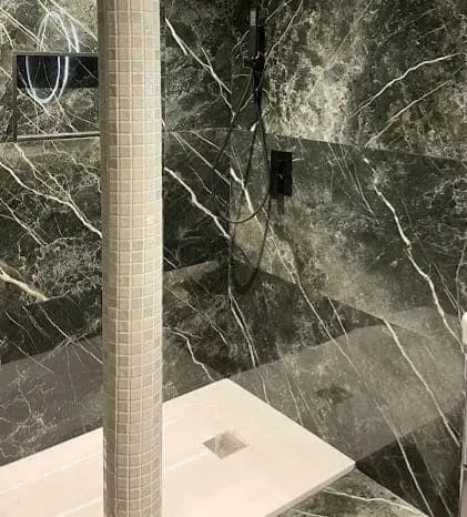 Un baño con azulejos de mármol y cabina de ducha.