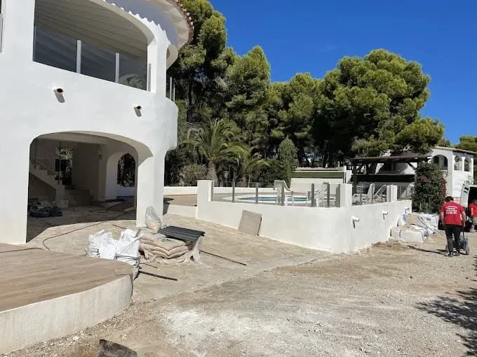 Un hombre con una camisa roja camina frente a una gran casa blanca.