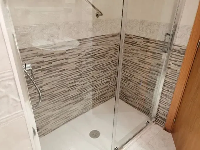Un baño con ducha a ras de suelo y puerta de cristal.