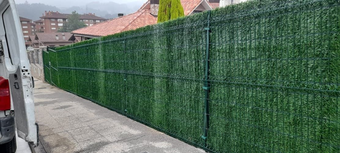 Una furgoneta blanca está aparcada junto a una valla verde.