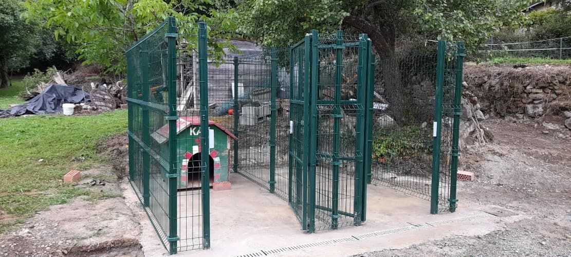 Una valla verde rodea un túnel en un parque.