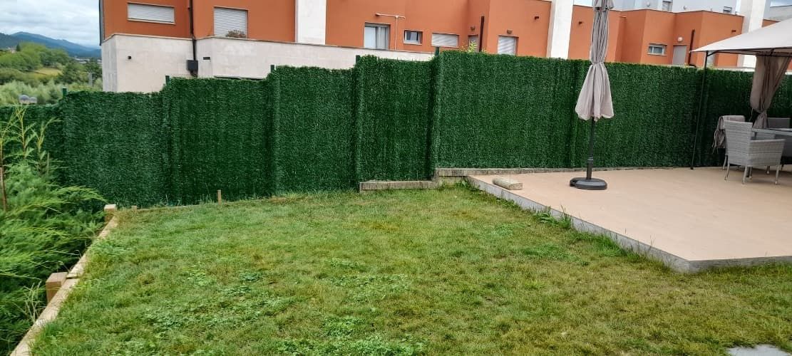 Un jardín con valla y un patio delante de un edificio.