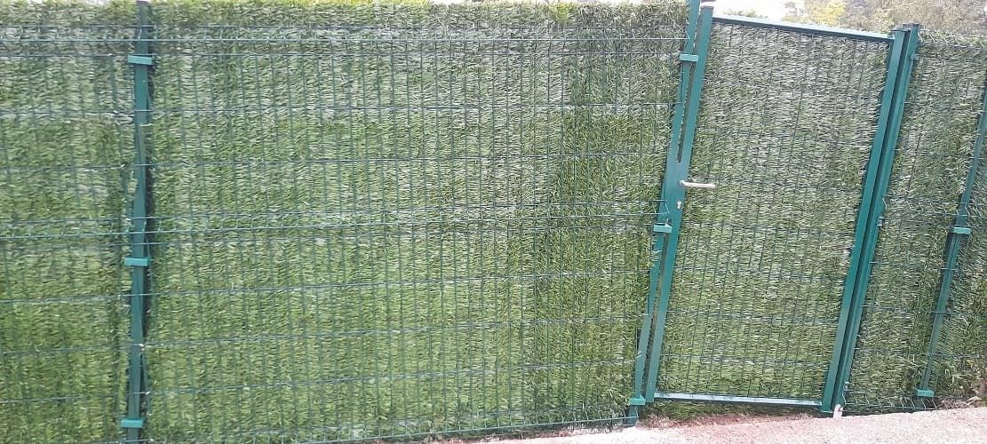 Una valla de seto verde con una puerta en el medio.