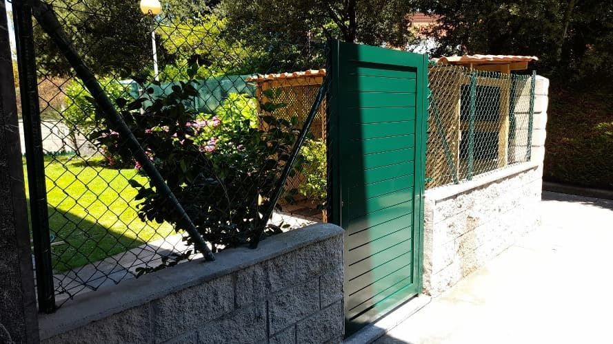 Una puerta verde con una valla de alambre detrás.