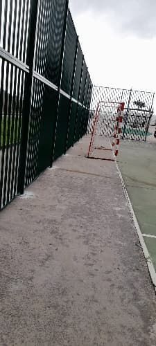 Una valla rodea una cancha de baloncesto en un parque.