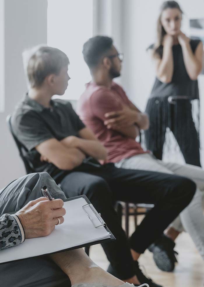 Personas en una sesión de terapia grupal, con una persona hablando y las demás escuchando atentamente.